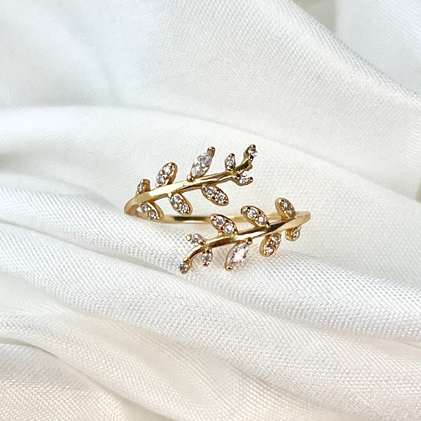 The Leaf Crown Encompassing Ring features a beautiful, nature-inspired design with delicate leaves encircling the finger, creating a crown-like effect. The intricate detailing and graceful leaf motifs evoke the beauty of nature, symbolizing growth, renewal, and the interconnectedness of life. This elegant ring offers a unique blend of sophistication and organic charm, perfect for those who appreciate nature's beauty and wish to wear a piece of timeless elegance. Whether worn as a statement piece or a subtle